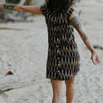 Woman walking in the sand under palm trees wearing a Vibrant short dress crafted from handloomed Ikat cotton