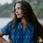 Woman wearing a blue Ikat cotton dress with a V-neckline, walking along the shoreline, showcasing artisan makers of handwoven fabric