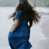 Blue Ikat cotton dress worn by a woman on the beach, highlighting its lightweight, sustainable design and artisan craftsmanship.