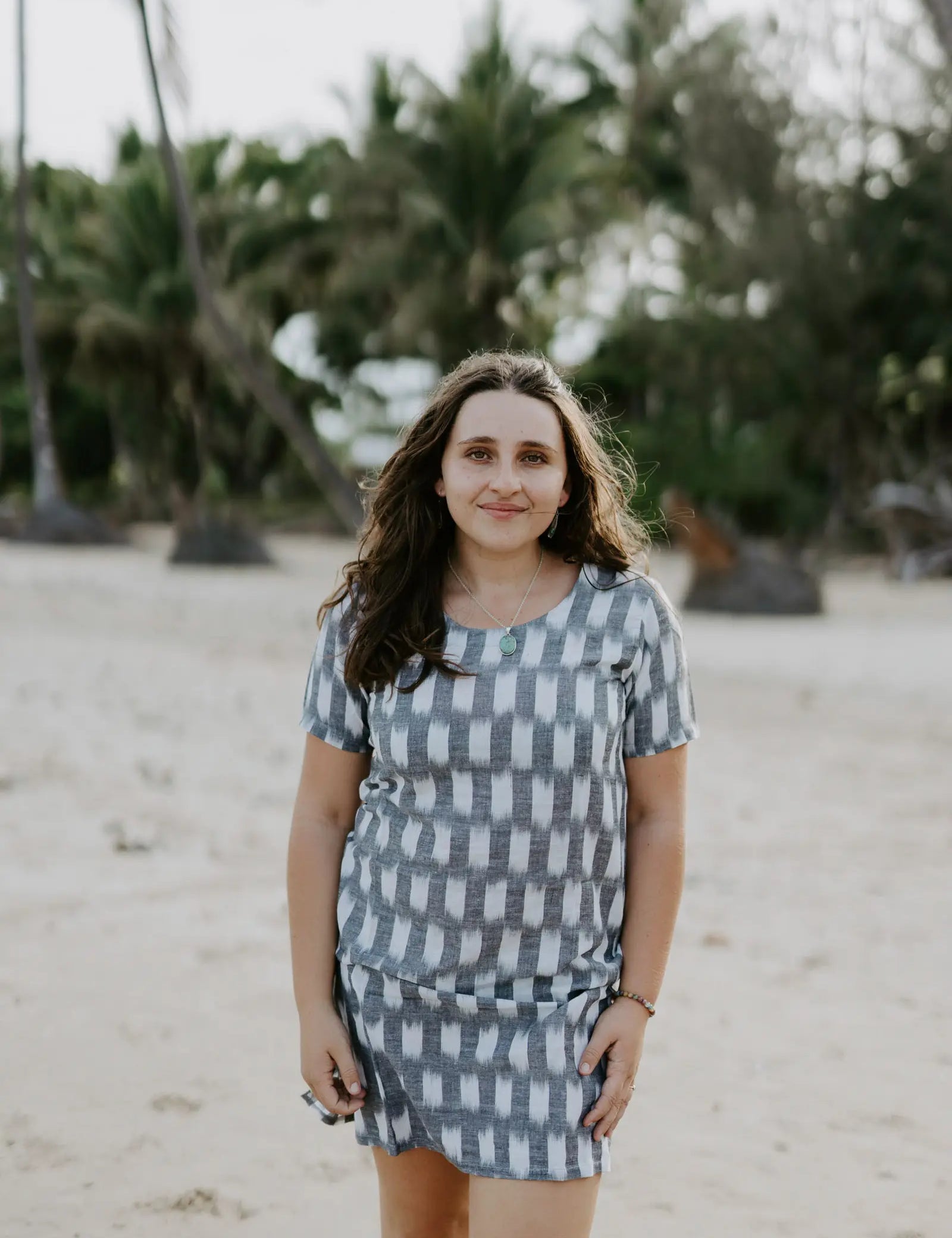 Woman wearing Carrie Short Dress on the beach in grey and white Ikat cotton.