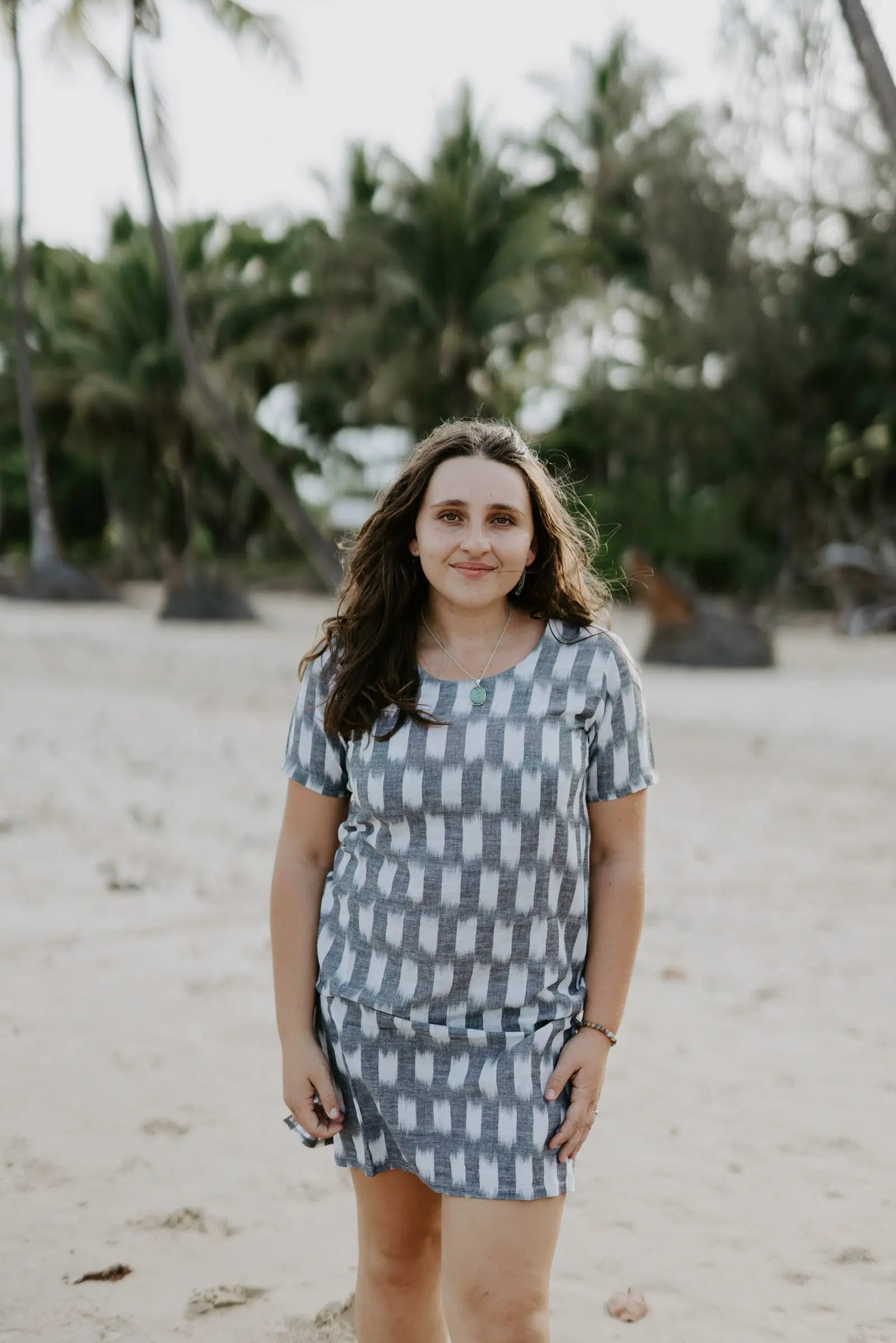 Woman wearing Carrie Short Dress on the beach in grey and white Ikat cotton.