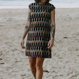 Red, mustard, and black artisan shift dress styled on the beach. 