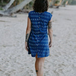 Woman wearing Tara Shirt shift dress walking away under coconut palms in the beach sand. mother of pearl buttons