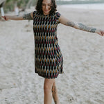 Woman walking on the beach wearing the Tara Shirt Dress in red, mustard, and black Ikat