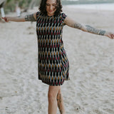 Woman walking on the beach wearing the Tara Shirt Dress in red, mustard, and black Ikat