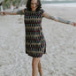 Woman walking on the beach wearing the Tara Shirt Dress in red, mustard, and black Ikat